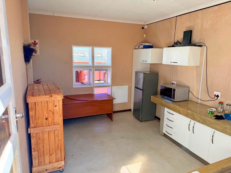 A functional industrial kitchen area featuring built-in cabinetry, a concrete countertop, and wall-mounted storage units.