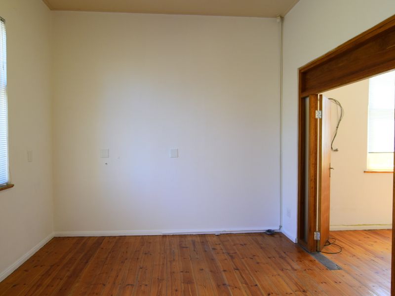 An empty office space featuring original timber flooring, timber door frames, and venetian blinds, requiring minor cosmetic updates and electrical finishing.