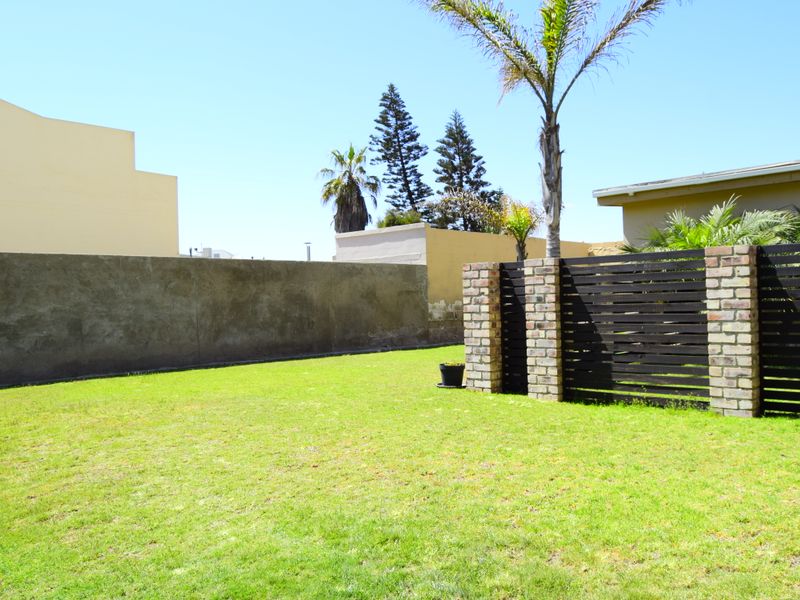 A private garden area featuring a lawn, brick boundary walls, and timber slat fencing with brick pillars.