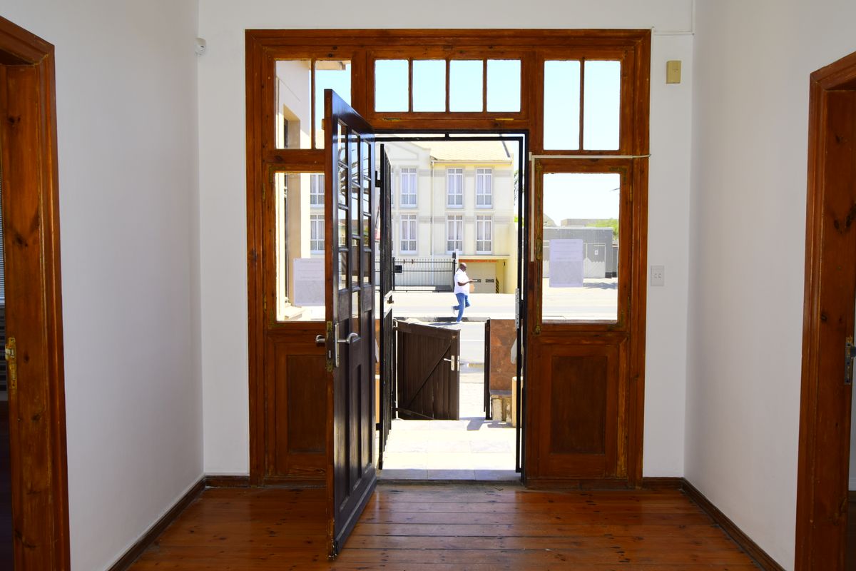 A bright entrance foyer featuring polished timber flooring and a classic timber-framed door with transom windows, providing a welcoming transition to the exterior.