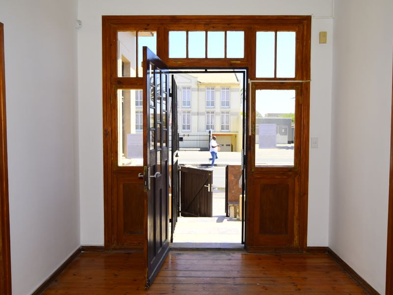 A bright entrance foyer featuring polished timber flooring and a classic timber-framed door with transom windows, providing a welcoming transition to the exterior.