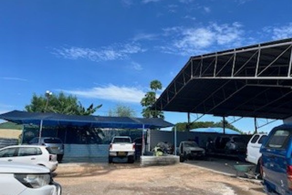 Industrial outdoor yard featuring extensive covered parking areas with steel frame structures and gravel ground surfacing.