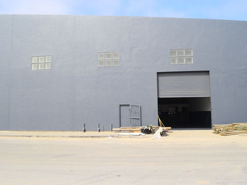 Front elevation of an industrial warehouse building featuring a large roller shutter door, security access door, and glass block windows.