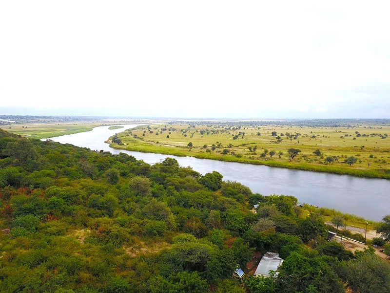 An elevated aerial view showcasing the expansive river and surrounding natural landscape, highlighting the scenic location of the lodge.