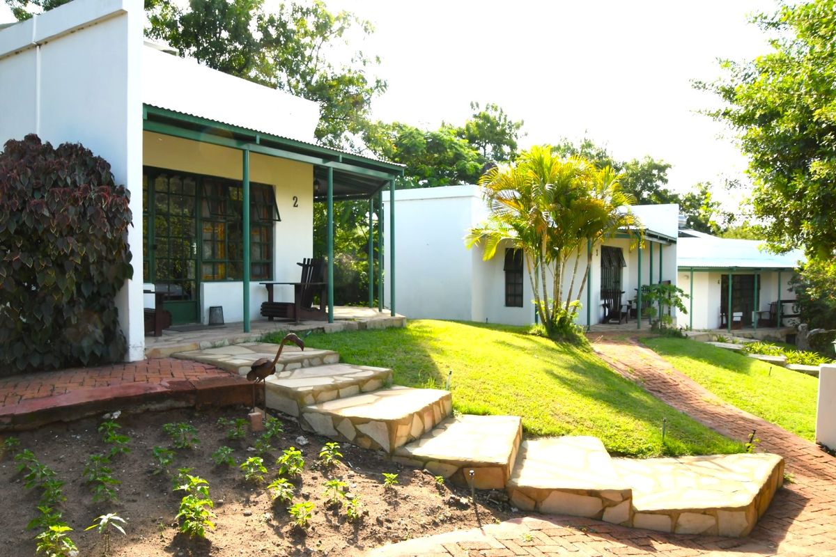 A view of the lodge exterior featuring covered patios, stone steps, and brick pathways leading to the individual guest units.