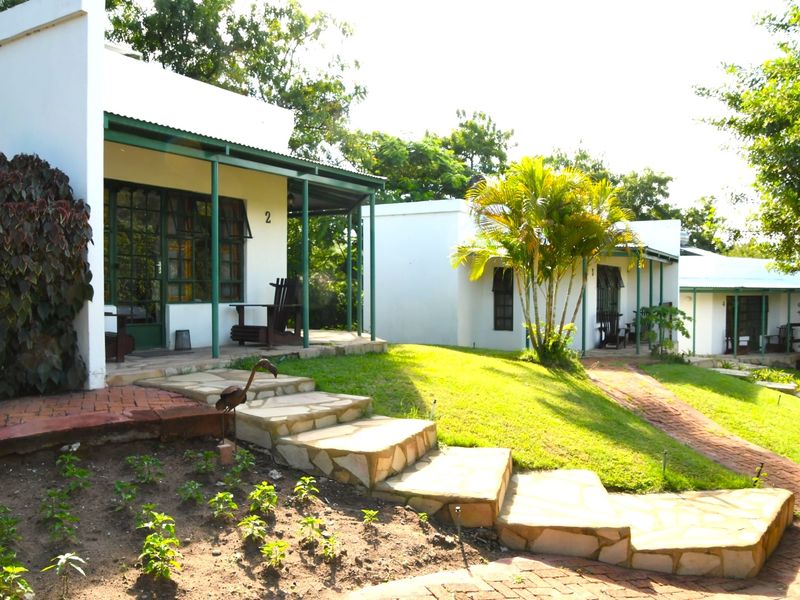 A view of the lodge exterior featuring covered patios, stone steps, and brick pathways leading to the individual guest units.