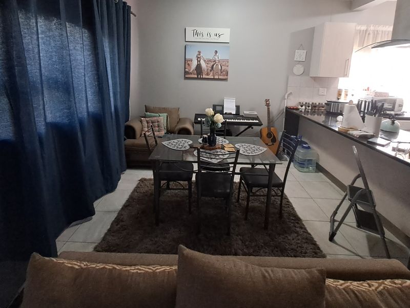 Open-plan living and dining area featuring tiled flooring and a functional kitchen with granite countertops and built-in cabinetry.
