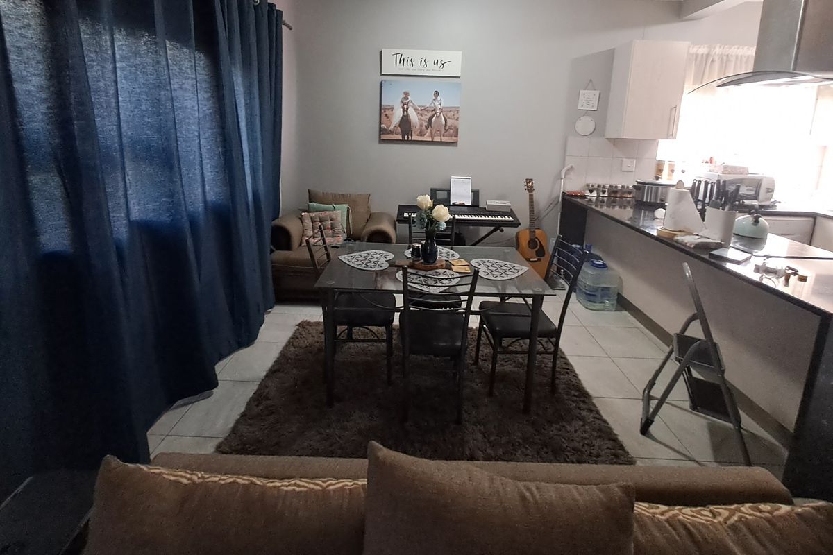 Open-plan living and dining area featuring tiled flooring and a functional kitchen with granite countertops and built-in cabinetry.