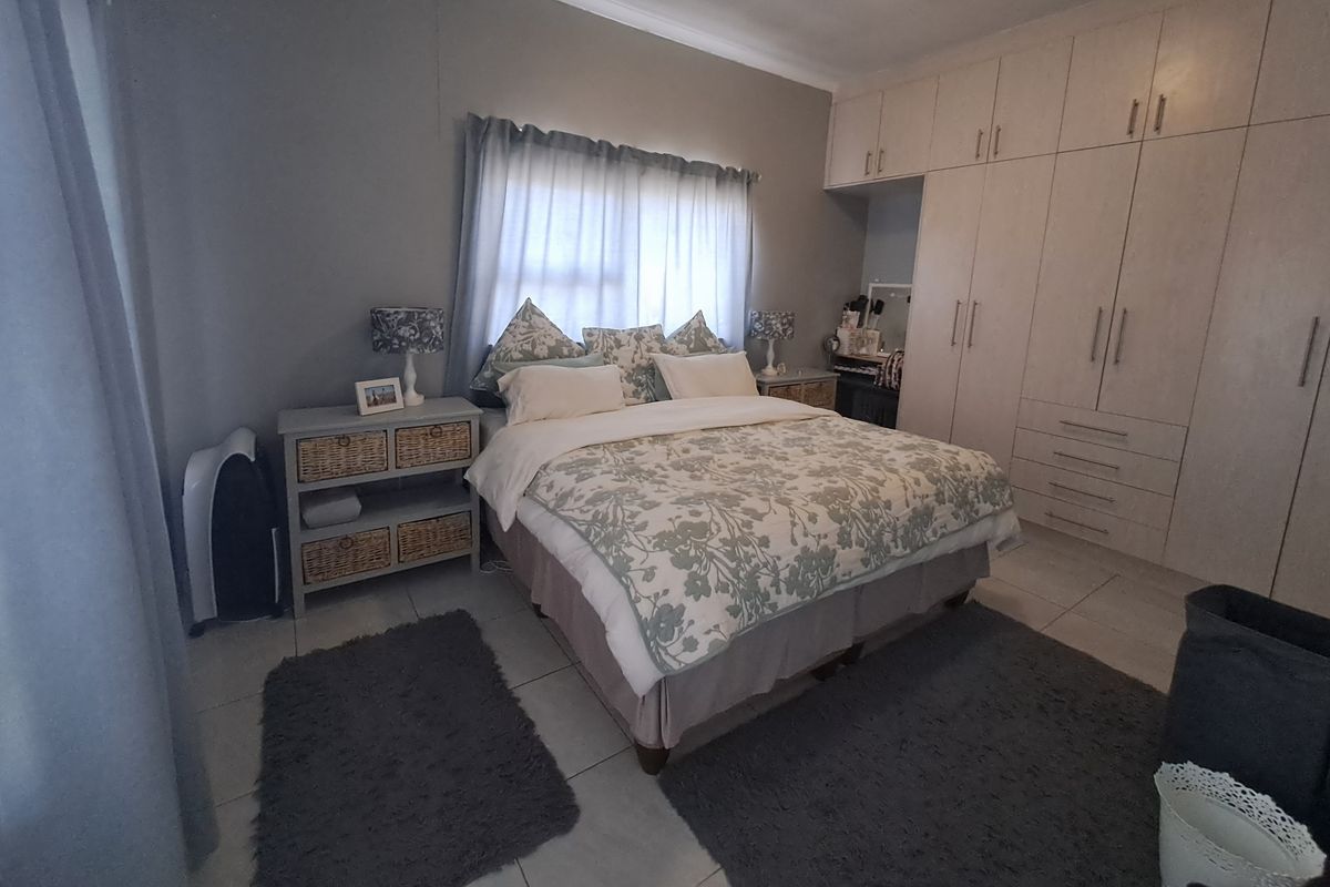 A well-maintained bedroom featuring neutral tiled flooring, ample built-in cupboard storage, and classic cornice detailing.