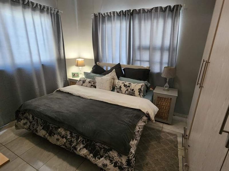 A functional bedroom featuring tiled flooring, neutral wall tones, and a built-in wardrobe with modern handles.