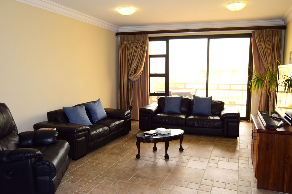 A spacious living room featuring large sliding glass doors that provide natural light and access to an outdoor area, finished with tiled flooring.