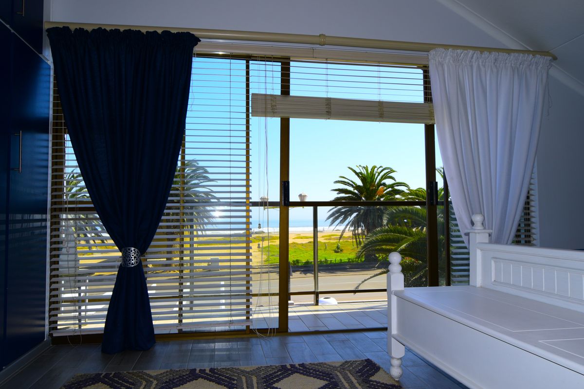 Bedroom featuring large sliding glass doors that open onto a balcony with scenic coastal and palm tree views.