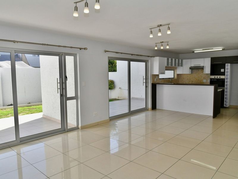 Spacious open-plan living and kitchen area featuring large sliding doors leading to the patio, tiled floors, and modern built-in kitchen cabinetry.