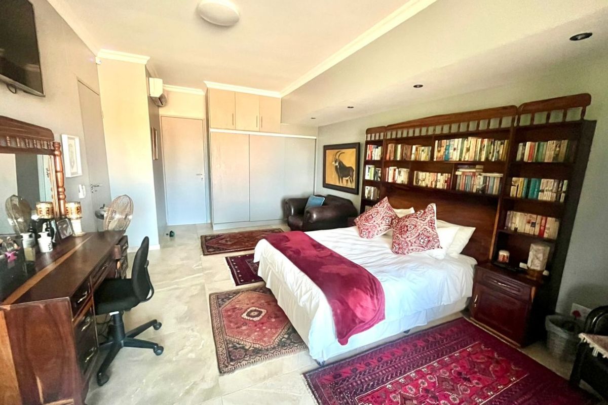 Spacious bedroom featuring built-in cupboards, recessed ceiling lighting, and tiled flooring, offering a comfortable and functional living space.
