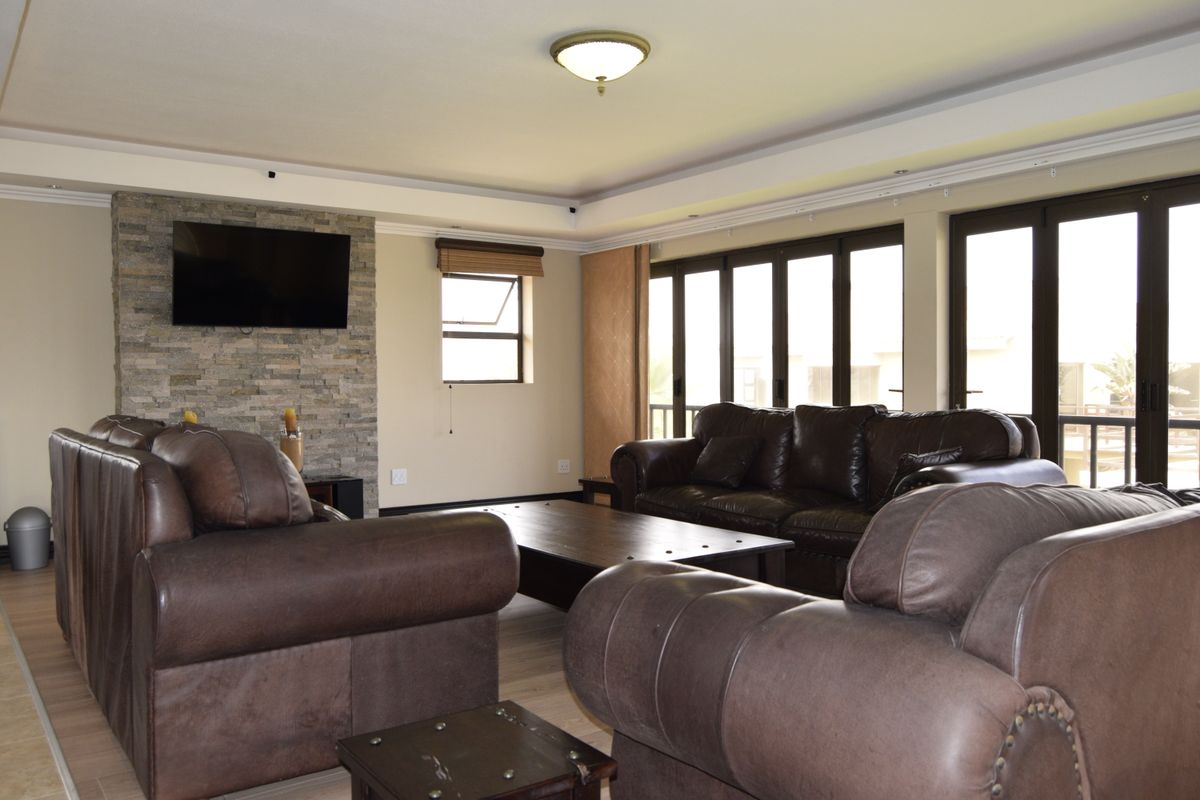Spacious living room featuring a stone-clad feature wall, recessed ceiling lighting, and large glass sliding doors providing ample natural light.