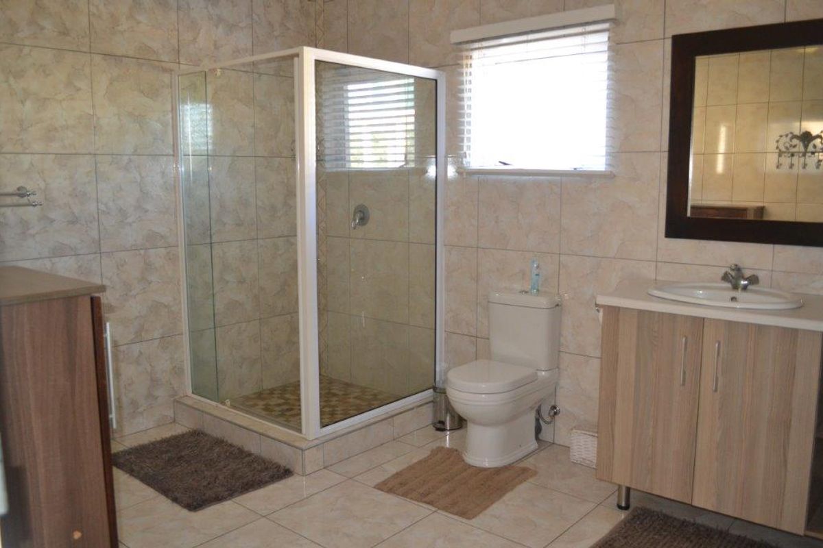 A functional bathroom featuring a glass-enclosed shower, a standard toilet, and a vanity cabinet with a basin.