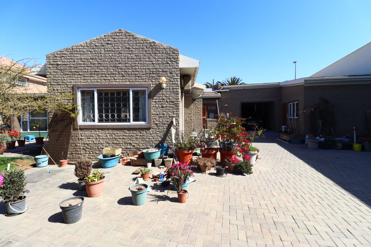 A paved rear courtyard area featuring brick exterior walls, a garage entrance, and security bars on the windows.