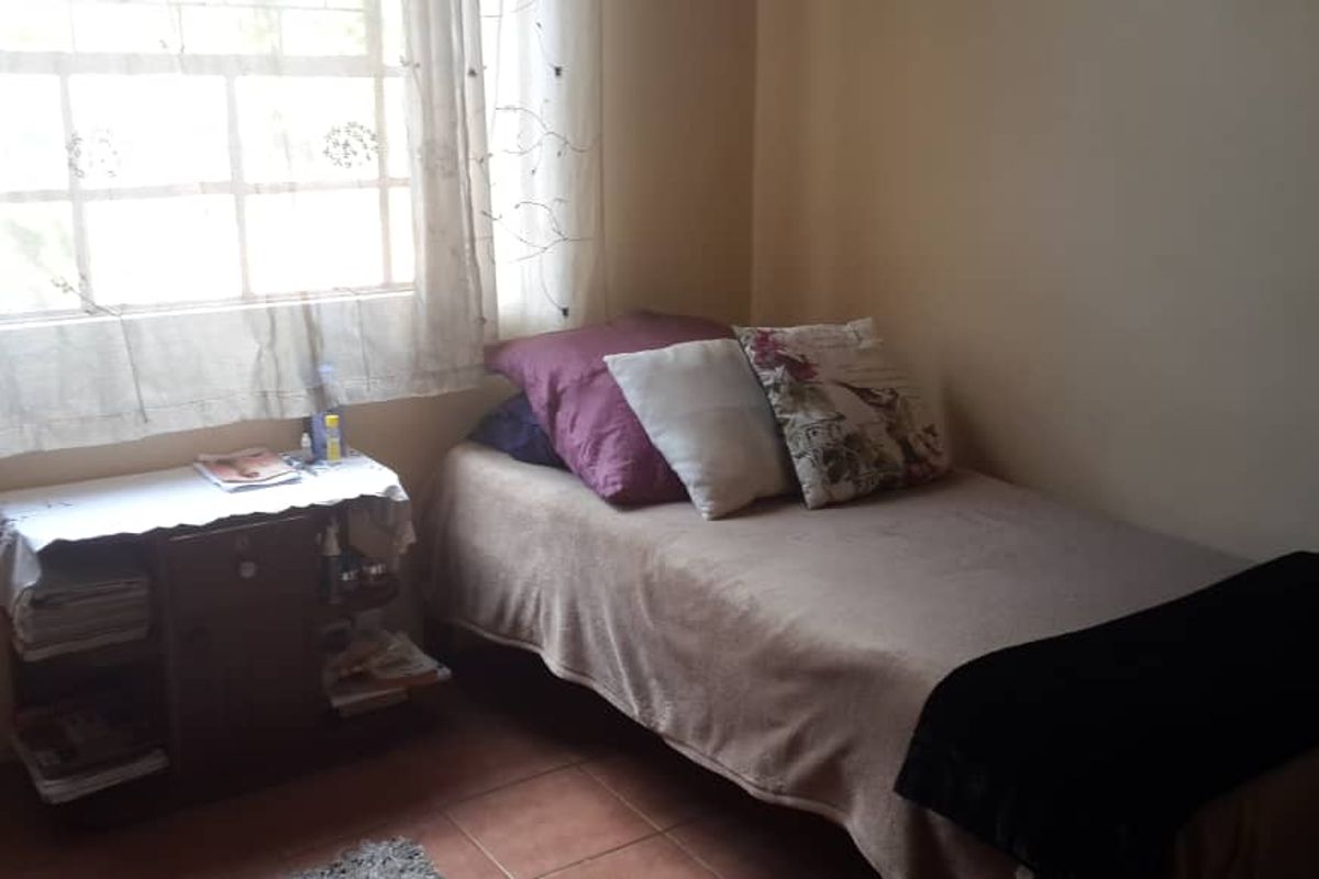 A functional bedroom featuring tiled flooring and a window with natural light, providing a simple and comfortable living space.