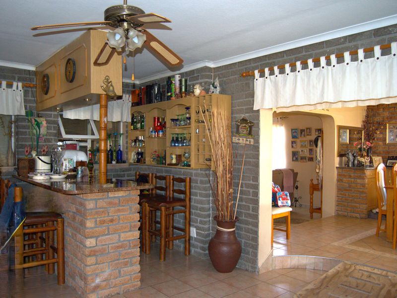 Open plan living area featuring a brick bar counter, built-in shelving, and exposed brick walls, connecting to an adjacent dining space through an archway.