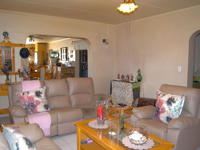 Open plan living area featuring tiled flooring and arched doorways connecting to the kitchen and dining space.