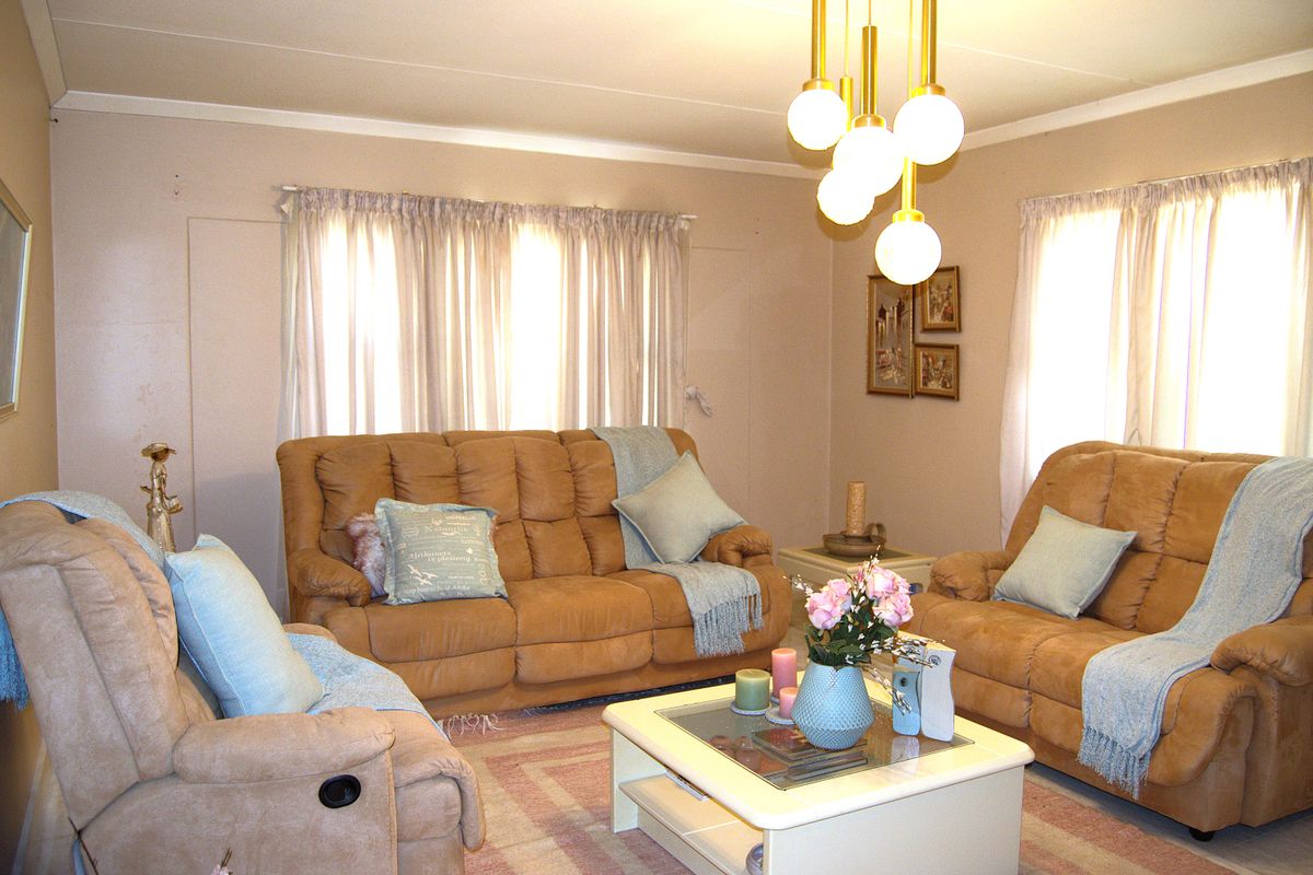 A comfortable living room featuring neutral wall tones, natural light through window treatments, and a distinctive multi-globe pendant light fixture.