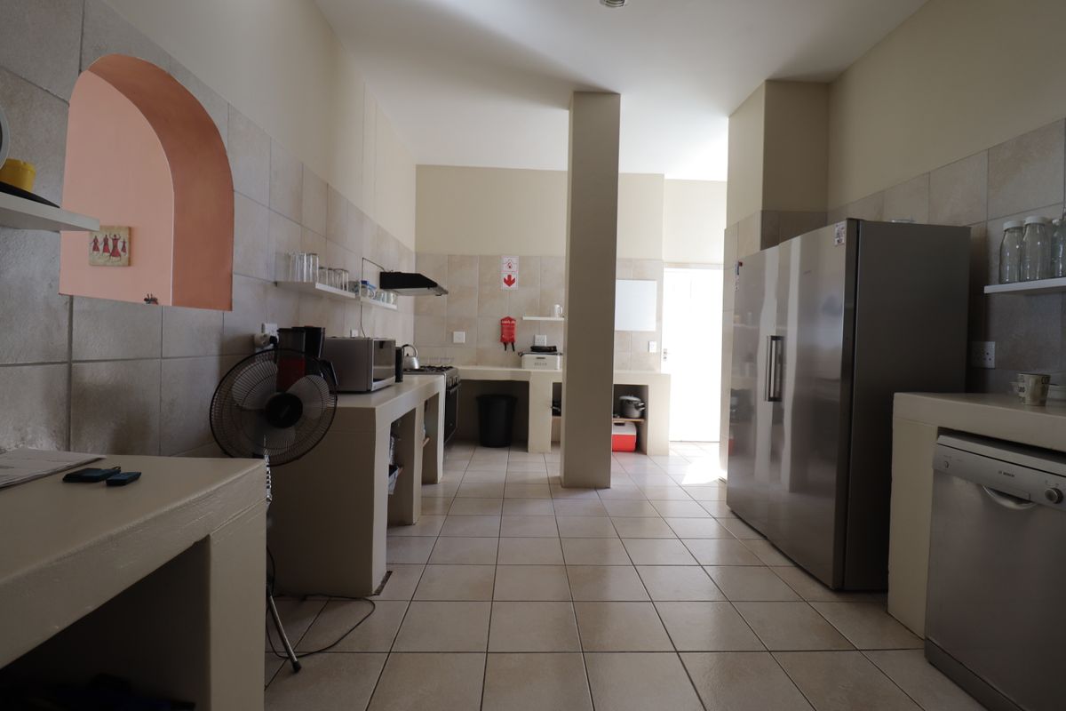 A functional kitchen featuring built-in masonry cabinetry, tiled flooring, integrated dishwasher, and stainless steel refrigerator.