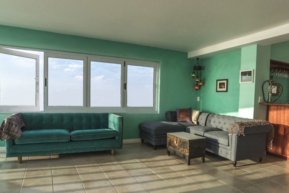 Spacious living area featuring large windows, tiled flooring, and an integrated wooden bar counter, offering a bright and open layout.