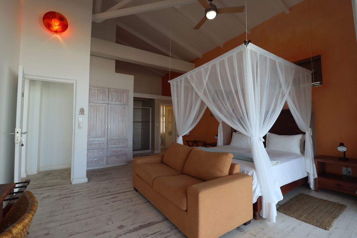 Spacious bedroom featuring vaulted ceilings, exposed beams, built-in wooden cabinetry, and an en-suite bathroom access.