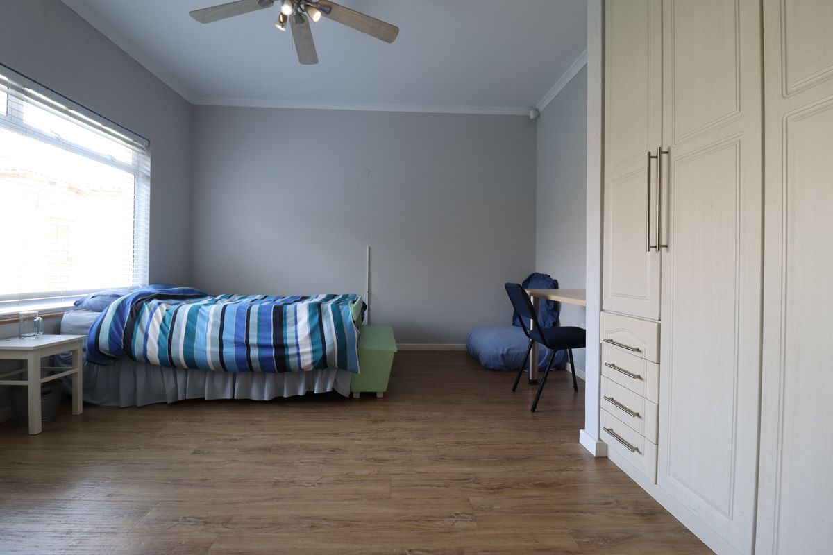 A well-maintained bedroom featuring wood-look flooring, built-in cabinetry with ample storage, and a ceiling fan.