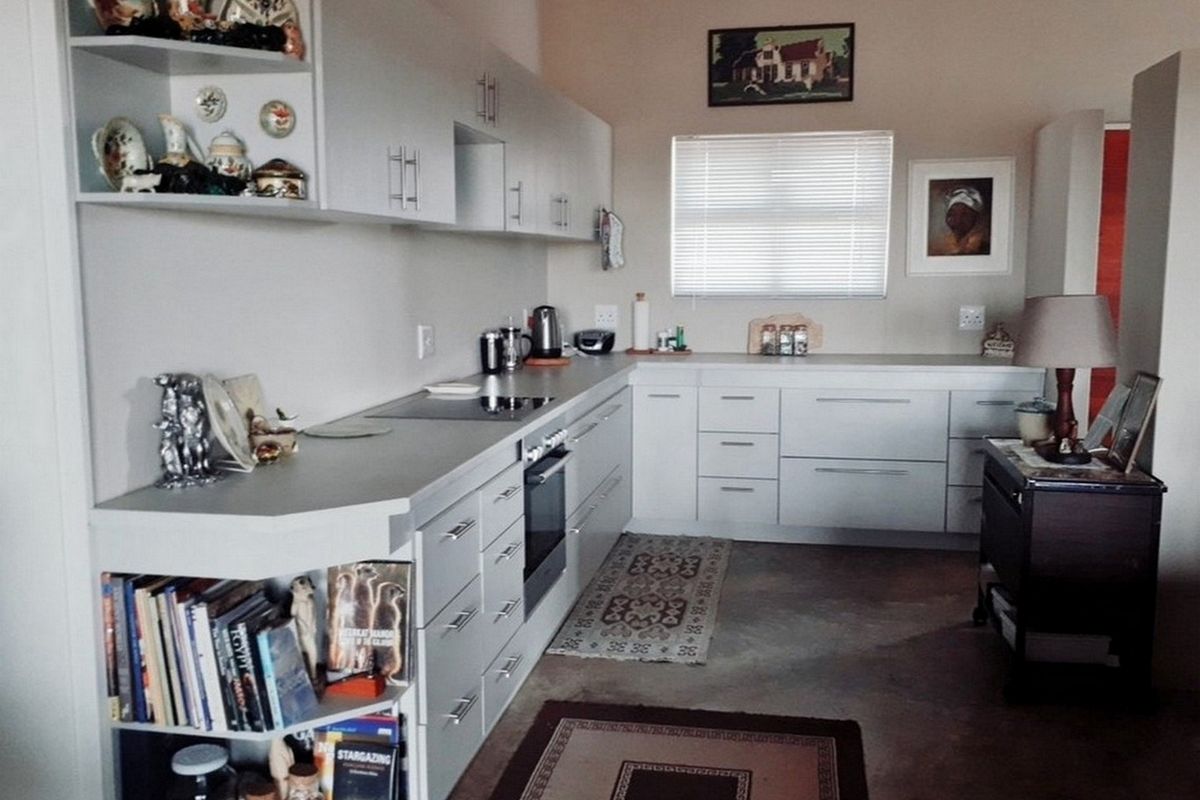 A functional kitchen featuring modern light-toned cabinetry, integrated oven and hob, and polished concrete flooring.