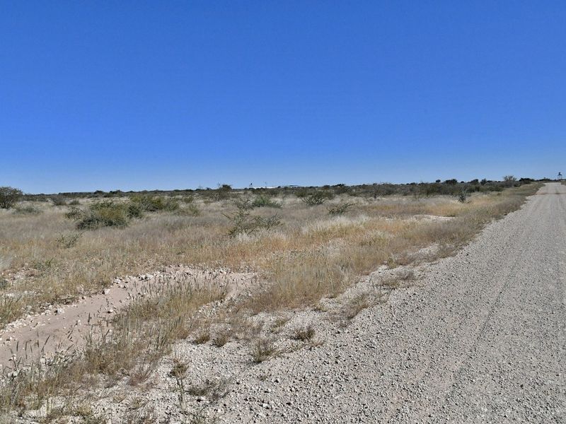 A view of a gravel access road leading through the open, undeveloped landscape of the small holding.