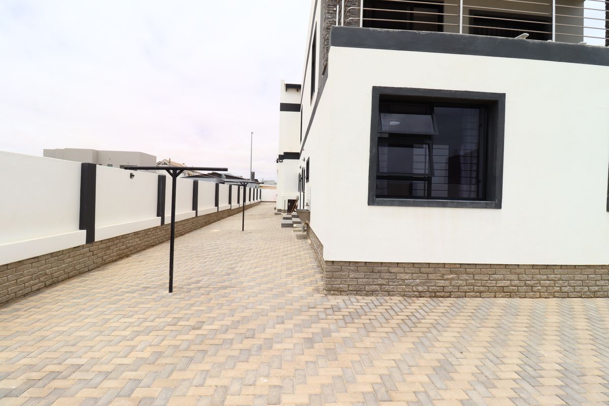 A paved side exterior area featuring a boundary wall, modern exterior finishes, and a functional outdoor space.