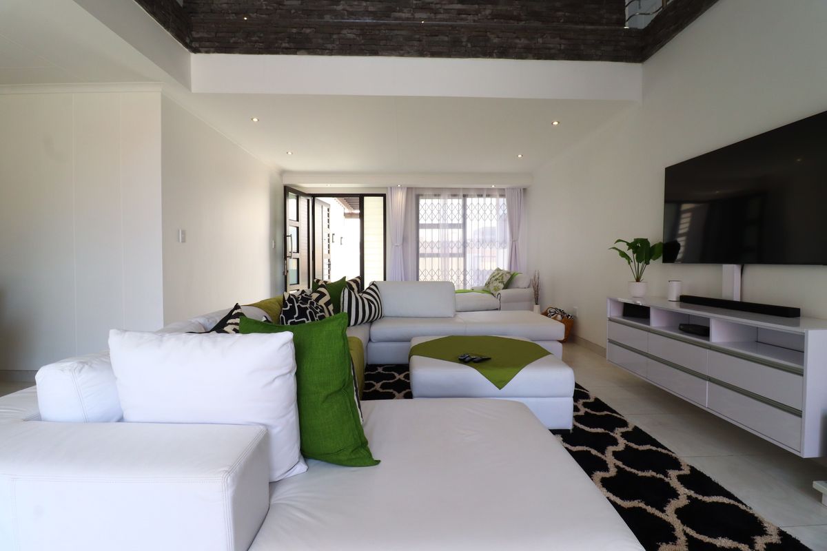 Spacious living room featuring tiled flooring, recessed ceiling lighting, and a decorative stone-cladding accent border along the upper wall perimeter.