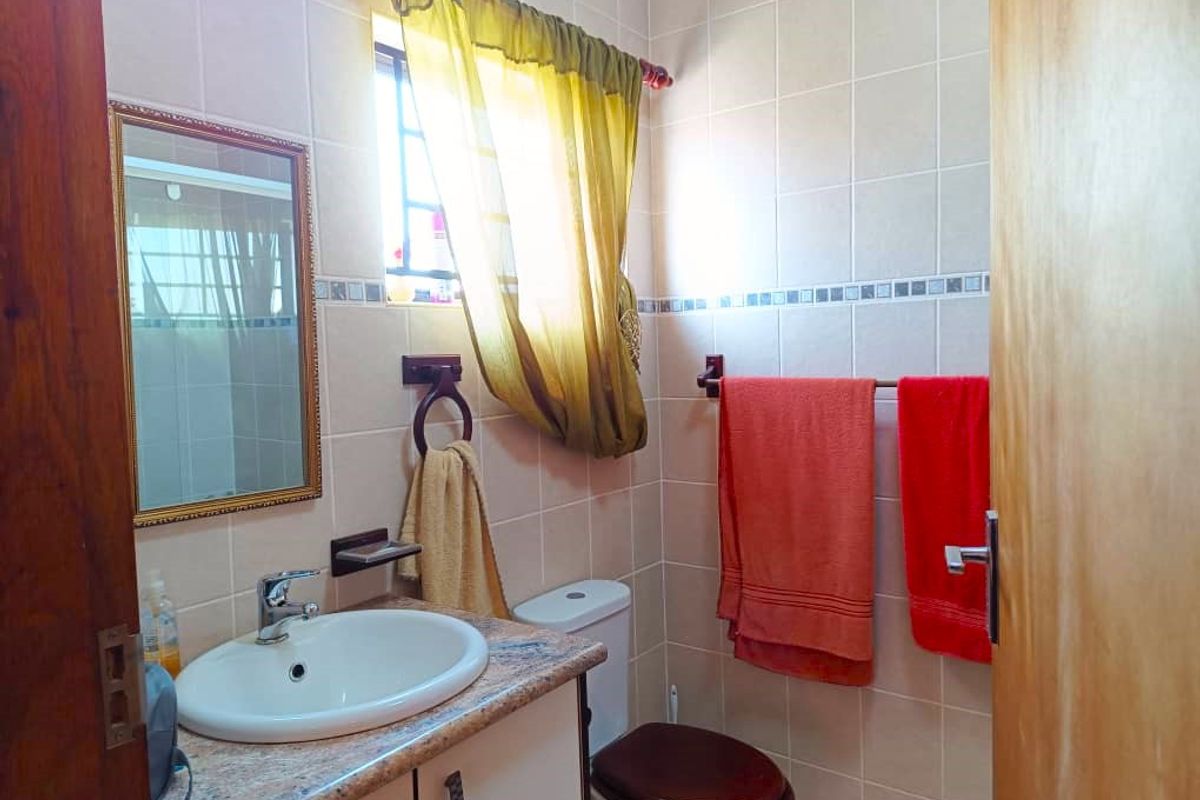 A compact bathroom featuring a vanity with a basin, a toilet, and tiled walls.