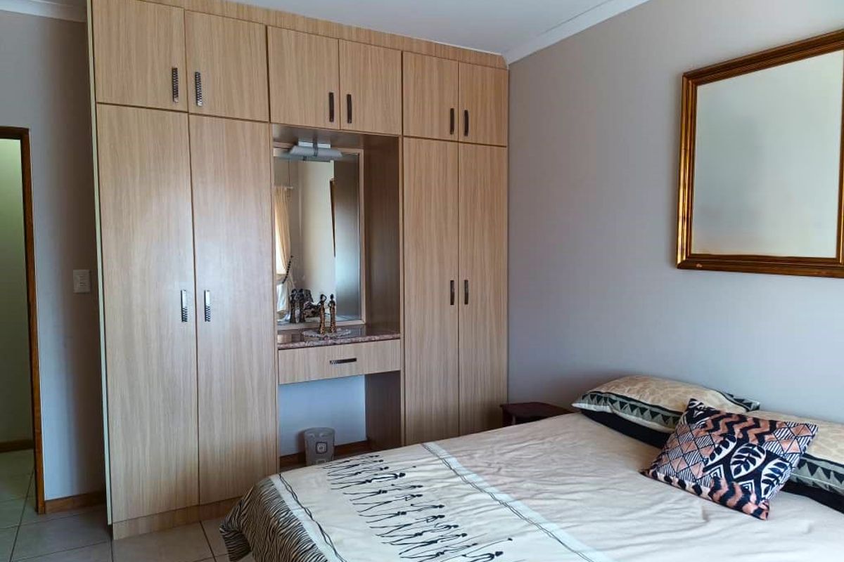 A well-maintained bedroom featuring extensive built-in light wood cabinetry with an integrated vanity and mirror.