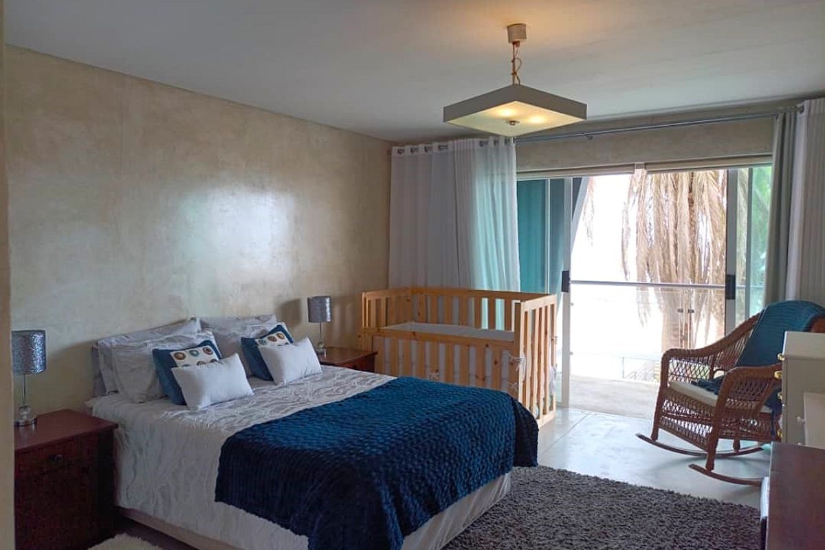 A bedroom featuring tiled flooring, a ceiling light fixture, and a sliding glass door providing access to an outdoor area.