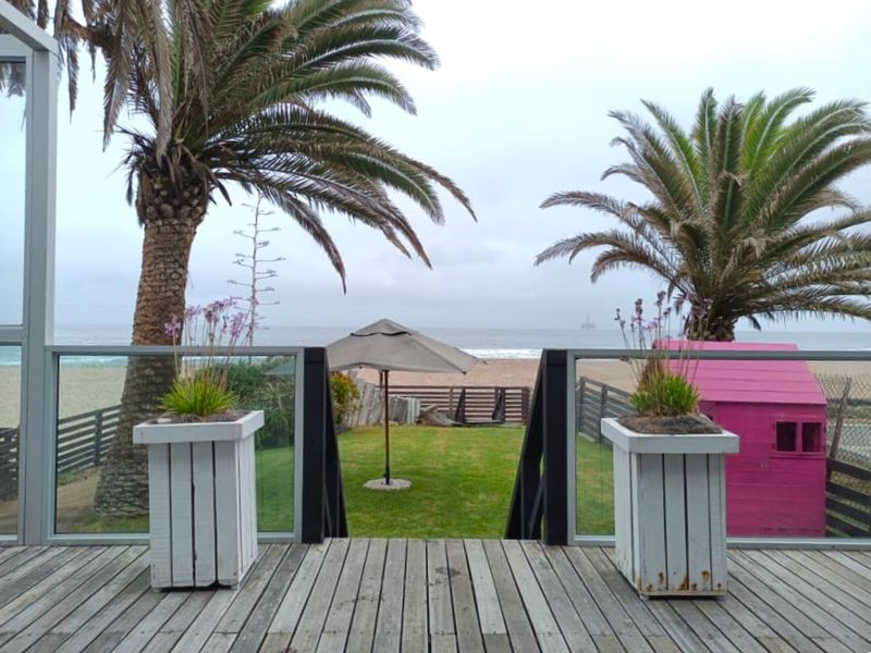 Elevated timber deck featuring a glass balustrade with direct views over the garden towards the beach.