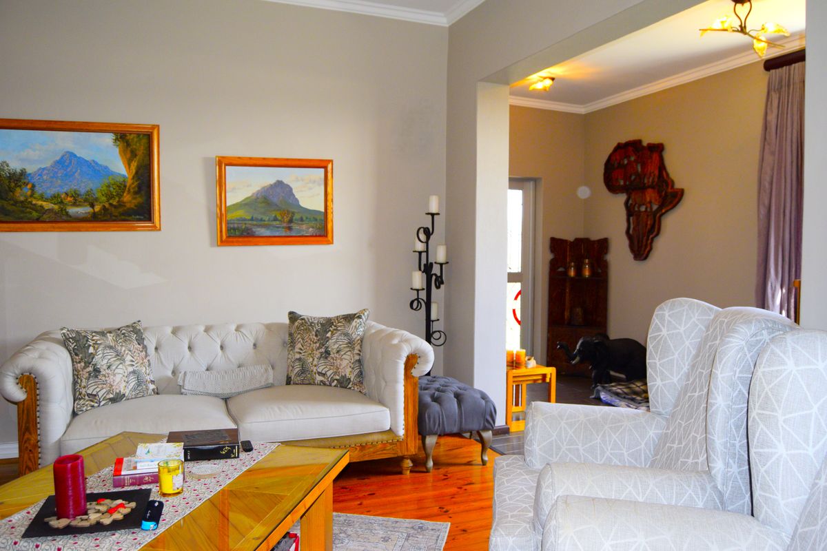 A comfortable living room featuring warm timber flooring and an open-plan layout that flows into an adjacent entryway.