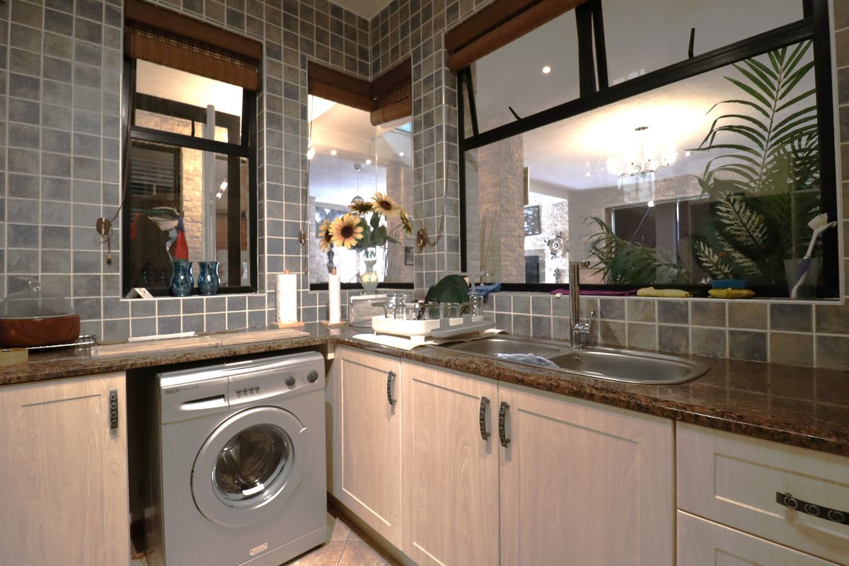 A functional kitchen area featuring granite countertops, tiled splashbacks, integrated cabinetry, and a built-in washing machine connection.