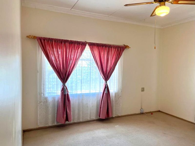 A vacant bedroom featuring a ceiling fan and carpeted flooring, offering a blank canvas for potential updates and personalization.