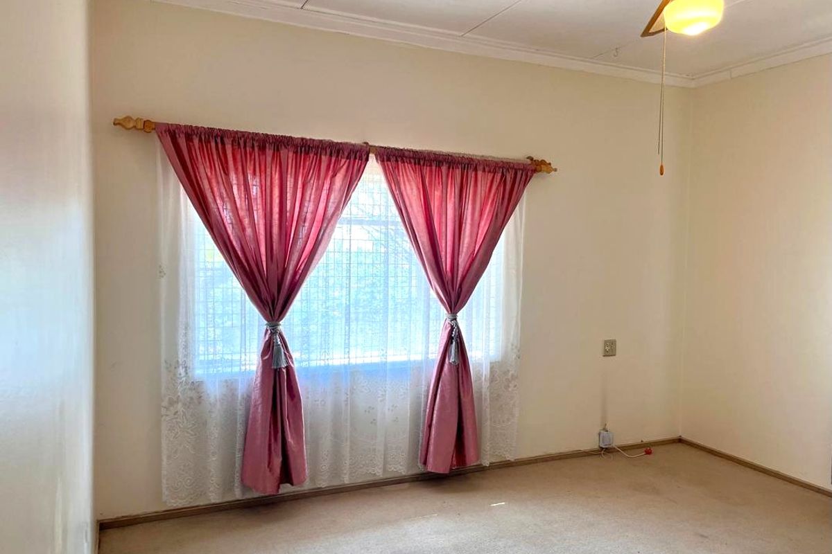 A vacant bedroom featuring a ceiling fan and carpeted flooring, offering a blank canvas for potential updates and personalization.