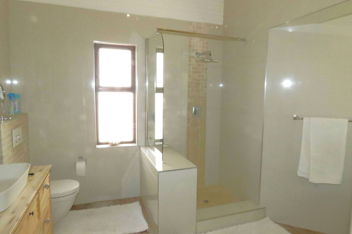 A modern bathroom featuring a walk-in shower with glass enclosure, a wall-mounted toilet, and a vanity unit with a vessel sink.