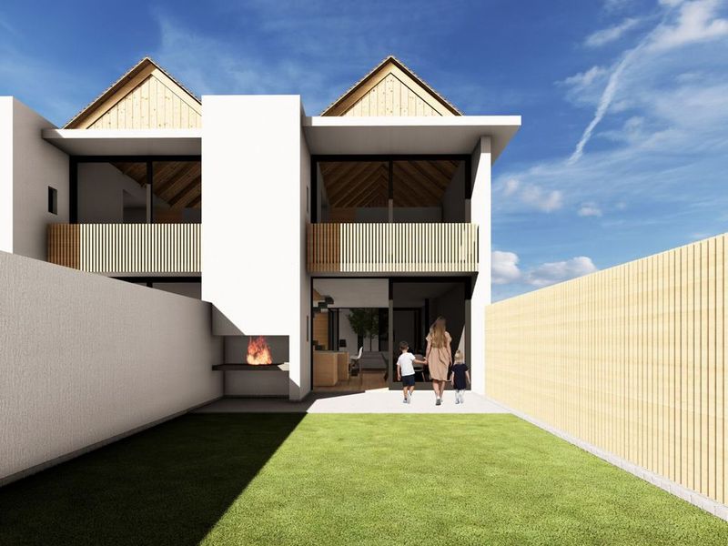 Rear view of a modern townhouse featuring a private garden, built-in braai, and upper-level balcony with timber detailing.