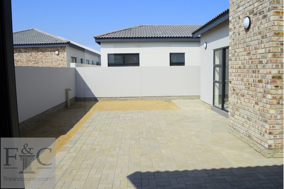 A private rear courtyard featuring paved flooring, perimeter boundary walls, and direct access to the main dwelling.