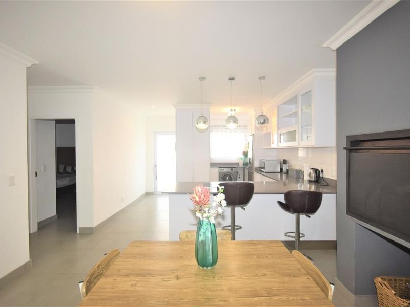 Open-plan living and kitchen area featuring modern cabinetry, a breakfast bar, and tiled flooring, creating a bright and functional space.