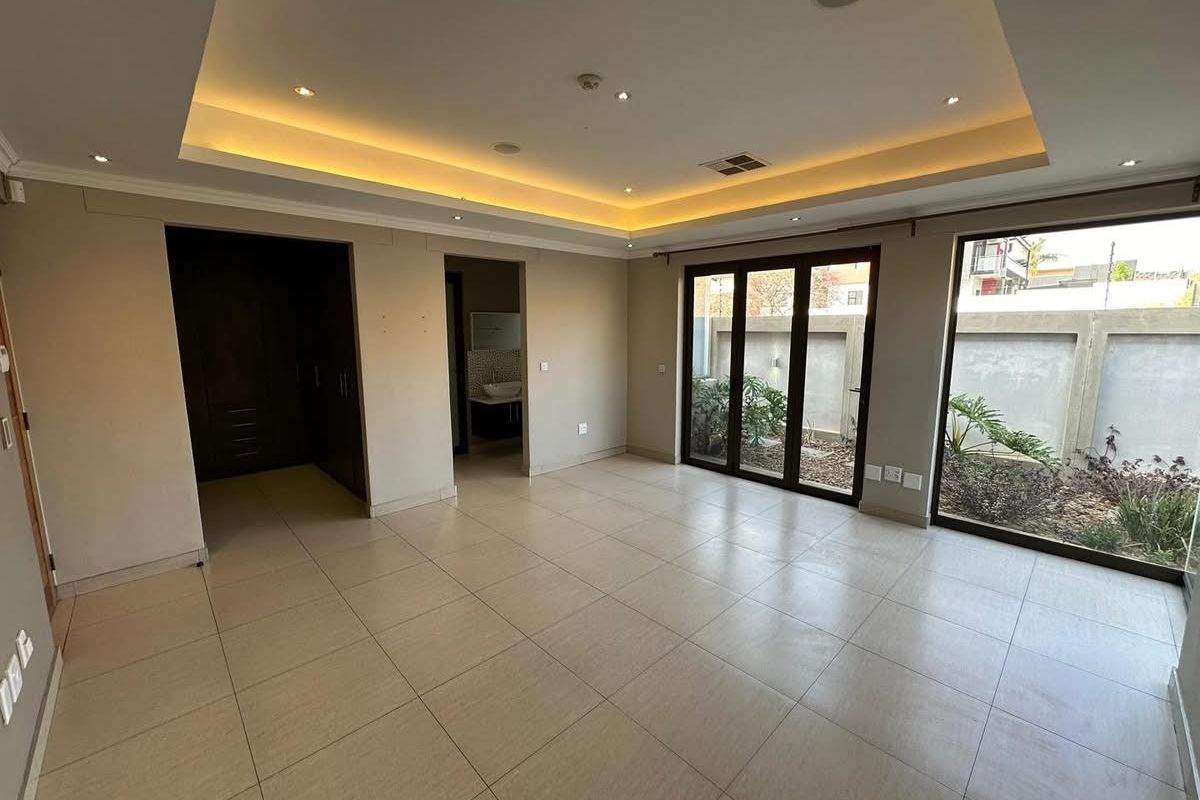 Spacious living area featuring recessed tray ceiling with integrated LED lighting, large glass sliding doors, and neutral floor tiling.