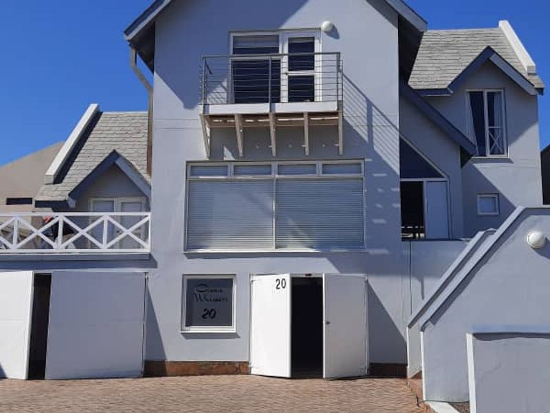 Front elevation of a multi-story residential property featuring a paved driveway, double garage access, and an upper-level balcony.