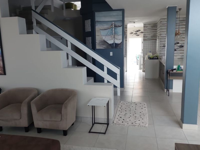 Open plan living area featuring a staircase, tiled flooring, and a view through to the kitchen area.