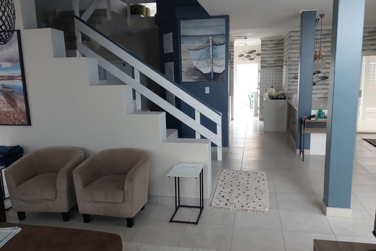 Open plan living area featuring a staircase, tiled flooring, and a view through to the kitchen area.