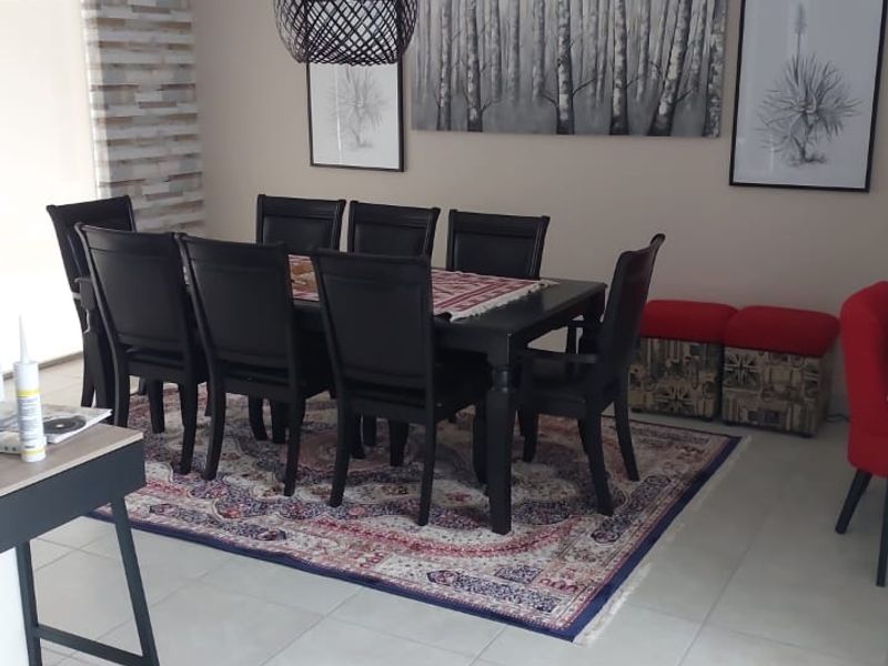 A well-lit dining area featuring neutral tiled flooring, a modern pendant light, and a textured feature wall, providing a comfortable space for family meals.